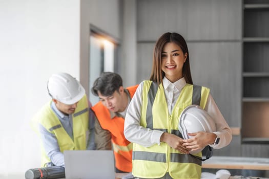 Civil engineer teams meeting working together wear worker helmets hardhat on construction site in modern city. Foreman industry project manager engineer teamwork. Asian industry professional team...