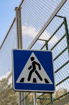 Tall modern lantern and crosswalk sign close up on blue sky background