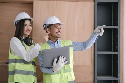 Structural engineer and architect dressed in reflective vests discuss the construction process by the chart and laptop...