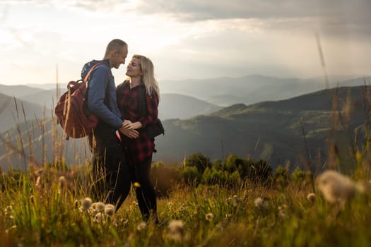 travel to mountains, tourists hikers with backpacks at sunset enjoying panoramic view.