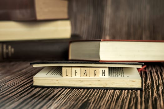 Pile of books, reading. Stack of books in the colored cover lay on the table. Open book with the text learn wooden background, education, reading, learning concept close up