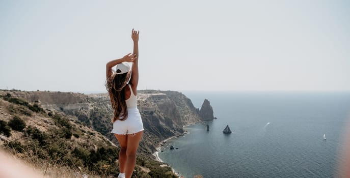 Woman travel sea. Young Happy woman in a long red dress posing on a beach near the sea on background of volcanic rocks, like in Iceland, sharing travel adventure journey