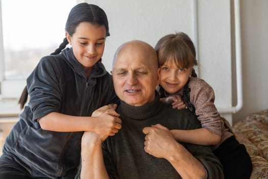 Ukrainian grandfather and two granddaughters hugging.