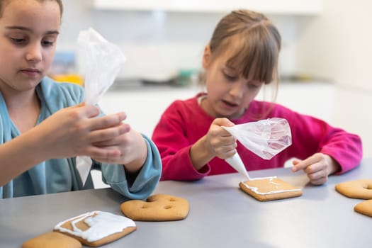 two little sisters decorating homemade cookies in the kitchen at home