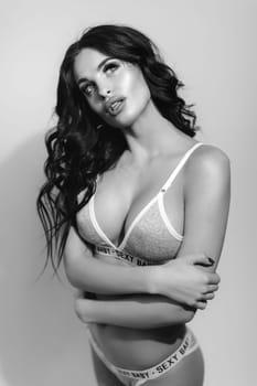 Sexy woman in lingerie with long curly black hair posing in studio. black and white