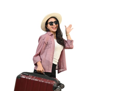 Smiling Asian woman wearing summer hat and sunglasses with luggage standing isolated white background.