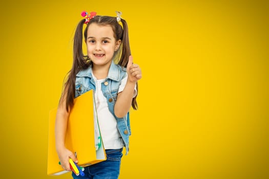 Portrait of stylish little girl with finger pointed up. Little child in striped shirt has idea. Kid isolated on yellow blackboard. Success, bright idea, creative ideas and innovation technology concep