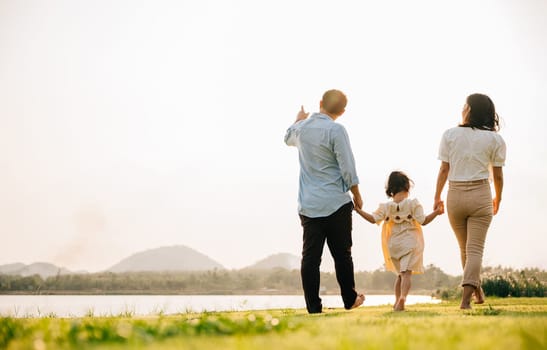 A family of four walking together in a beautiful park in Thailand, with a green nature background and a feeling of fun and excitement, Family day, back view