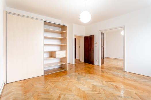 an empty room in an apartment with a wardrobe and a wooden parquet floor. High quality photo