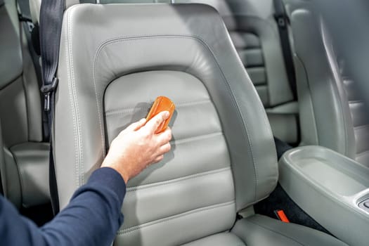 cleaning leather car seats with a brush and chemicals.