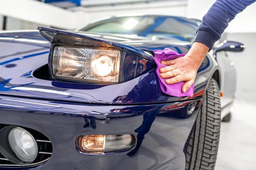 detailing and polishing the body of a luxury sports car using a microwipe. High quality photo