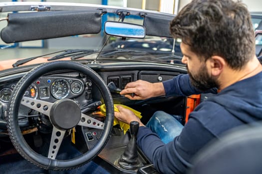 cleaning the interior of the old car with a brush and rag. High quality photo