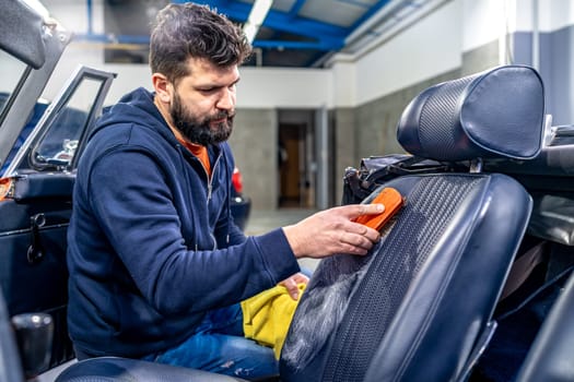 cleaning leather car seats with a brush and chemicals.