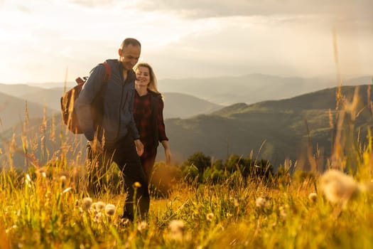 A man and a woman in tourist equipment are standing on a rock and admiring the panoramic view. A couple in love on a rock admires the beautiful views. A couple in love is traveling. A couple on a hike