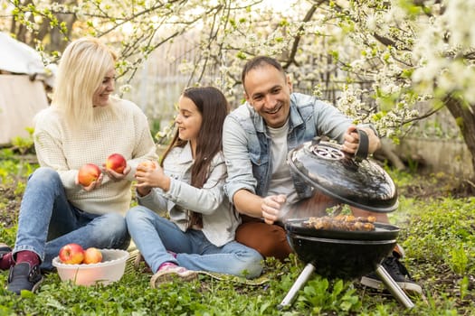 smiling parent grilling meat with daughter on camping.