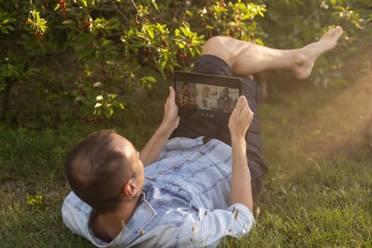 a man uses a tablet to chat in the garden.