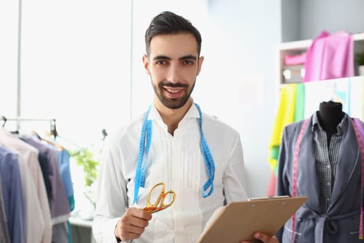 Portrait of male fashion designer stylist in atelier. Sewing fashionable modern clothes in creative workshop