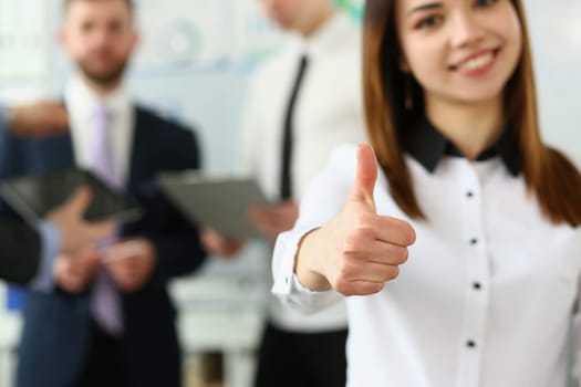 Businessman holds thumbs up in background are business partners. Recommendation of business consultant and quality company development services