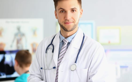 Portrait of smiling young doctor with a stethoscope on background of office in clinic. Medical services and insurance