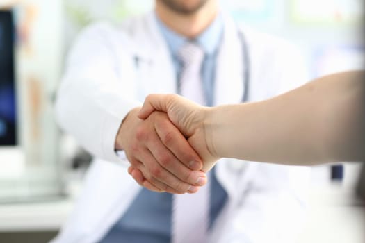 Doctor shaking hands with patient in clinic and thanking handshake for excellent treatment. Trust partnership and health insurance concept