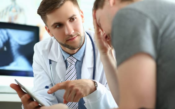 Doctor with tablet consults patient suffering from mental stress and depression. Medical diagnosis of fatal disease and communication to patient