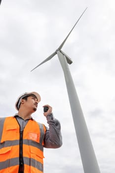 Engineer working on a wind farm atop a hill or mountain in the rural. Progressive ideal for the future production of renewable, sustainable energy. Energy generation from wind turbine.