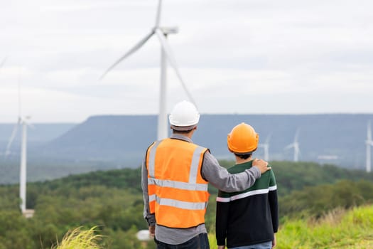 Engineer with his son on a wind farm atop a hill or mountain in the rural. Progressive ideal for the future production of renewable, sustainable energy. Energy generation from wind turbine.