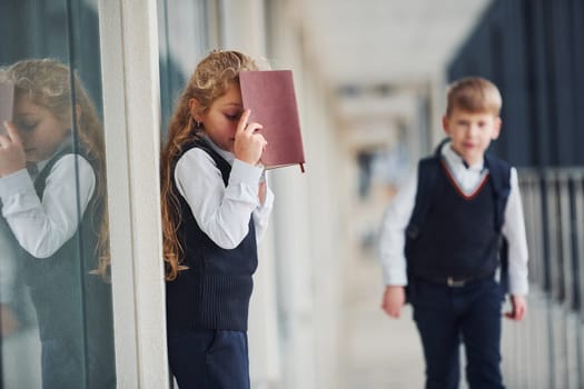 School kids in uniform with books together in corridor. Conception of education.