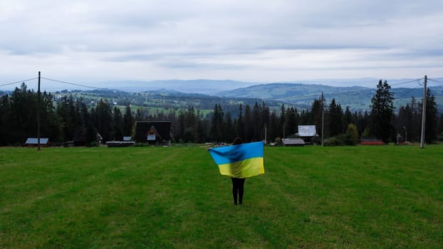 Woman with Ukrainian national flag waving Patriotism Aerial view of Zakopane town underneath Tatra Mountains taken from the Gubalowka mountain range. Drone High mountains and green hills in summer or spring. Scenic mountain view in Poland. Travel tourist destinations