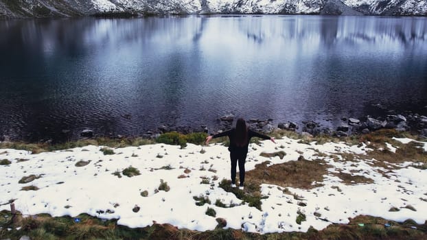 Happy woman enjoying Czarny Staw pod Rysamy or Black Pond lake near the Morskie Oko Snowy Mountain Hut in Polish Tatry mountains, drone view, Zakopane, Poland. Unity with nature Aerial view shot of beautiful green hills and mountains in dark clouds and reflection on the lake Morskie Oko lake. Travel tourist destination 4k