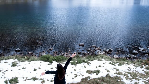 Happy woman enjoying Czarny Staw pod Rysamy or Black Pond lake near the Morskie Oko Snowy Mountain Hut in Polish Tatry mountains, drone view, Zakopane, Poland. Unity with nature Aerial view shot of beautiful green hills and mountains in dark clouds and reflection on the lake Morskie Oko lake. Travel tourist destination 4k