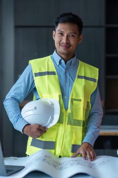 Asian engineer handsome man or architect looking forward with white safety helmet in construction site.