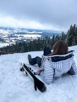 Shot of a skier woman sitting on the ski slope resting relaxing extreme recreation active lifestyle activity. Female skier on a slope in the mountains. Winter active sport Country cross skier in Alps