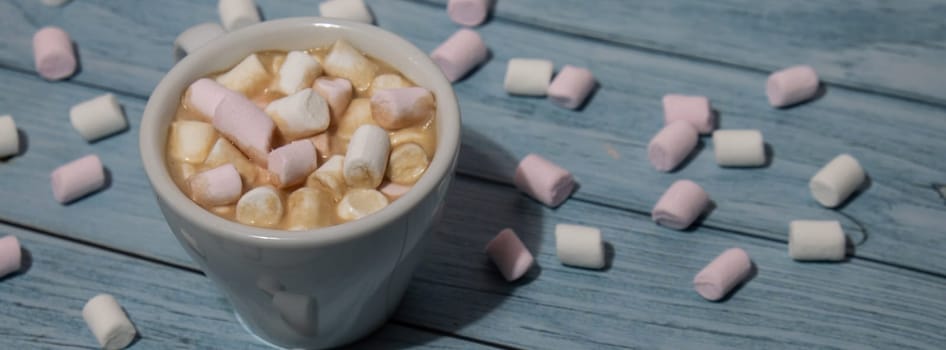 Banner Close up of Cup hot chocolate marshmallows cacao. Cozy Coffee with marshmallows on wooden blue background. Copy space for text. Wallpaper design. Sweet unhealthy food