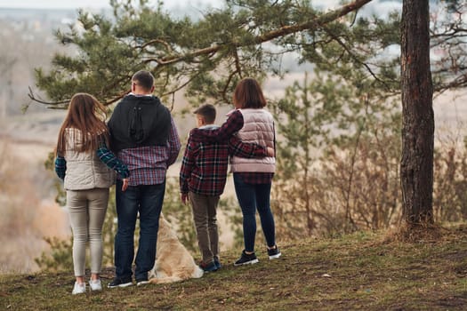 Rear view of family that standing together with their dog outdoors in forest.