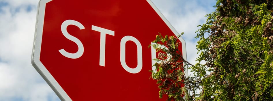 Red stop sign on metal pole on street. Road attention sign on cloudy background. Outdoors