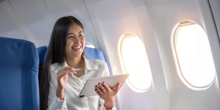 Beautiful asian travel woman watching movie on digital tablet in airplane.