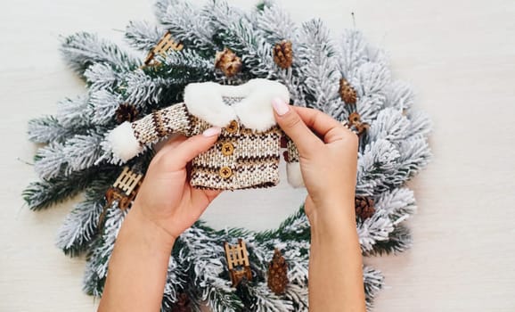 Woman's hands holds little sweater. Top view of christmas festive texture with new year decorations.