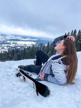 Shot of a skier woman sitting on the ski slope resting relaxing extreme recreation active lifestyle activity. Female skier on a slope in the mountains. Winter active sport Country cross skier in Alps