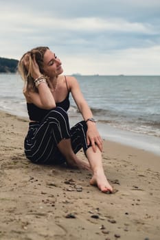 Young woman siting on blurred beachside background. Attractive female enjoying the sea shore. travel and active lifestyle concept. Springtime. Relaxation, youth, love, lifestyle solitude with nature. Wellness wellbeing mental health inner peace Slow life digital detox