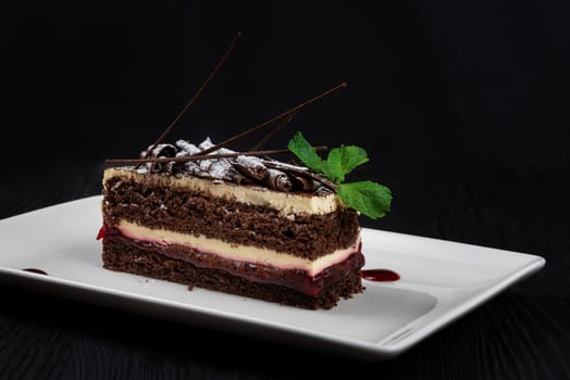 Chocolate cake decorated with mint leaves on black background