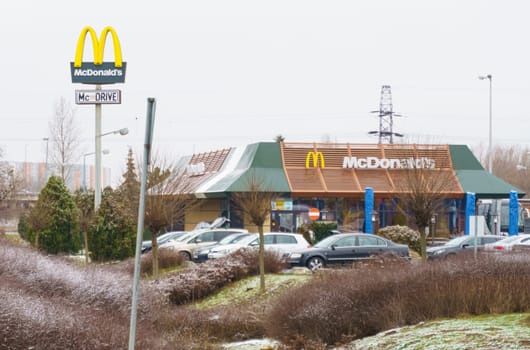 Poznan, Poland - January 25, 2023: McDonald's restaurant building with logo and car parking in winter