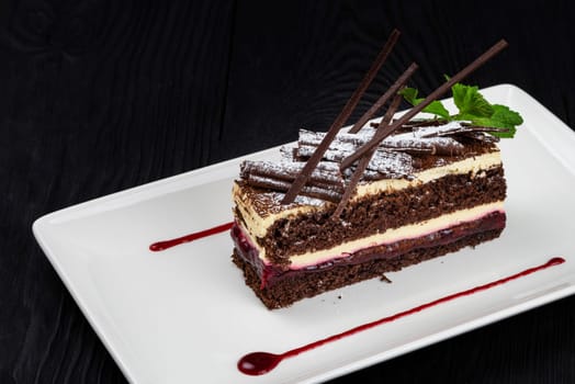Chocolate cake decorated with mint leaves on black background