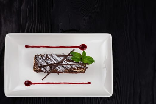 Chocolate cake decorated with mint leaves on black background