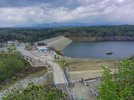 Aerial view of water dam against the hills and cloudy sky