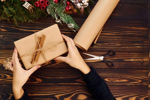 Woman's hands holds gift box. Top view of christmas festive texture with new year decorations.