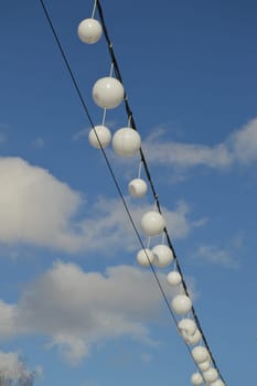 White garland balloons oscillate in the wind against blue sky and clouds, peaceful landscape