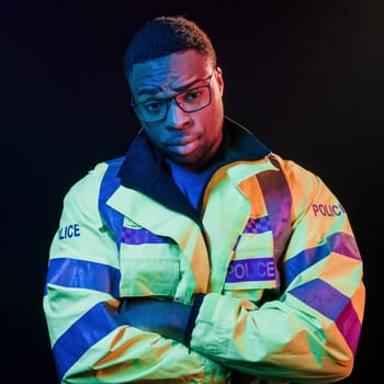 In police uniform. Futuristic neon lighting. Young african american man in the studio.