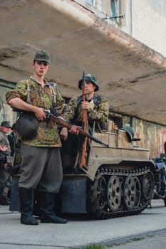 Hel, Poland - August 2022 Military troops marching during 3 May Polish Constitution Day ceremonial patriotic parade. Polish armed forces tanker military parade. Old guns and cars. Feast of Polish Armed Forces Day, American soldiers with US flag on parade Nato Vehicles Military Equipment