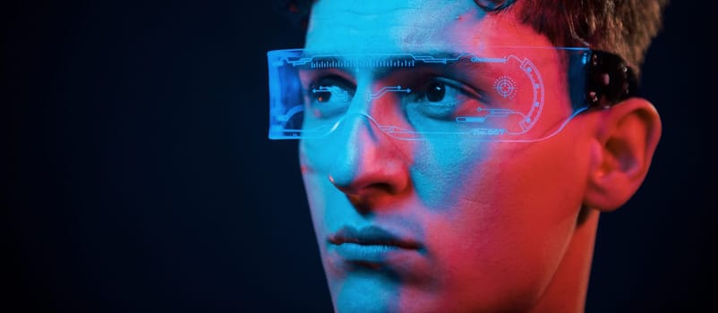 Close up portrait. Neon lighting. Young european man is in the dark studio.